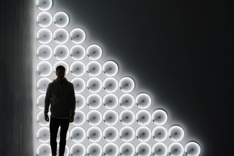 Mann steht vor einer Wand, die mit runden LED-Lichtern beleuchtet wird.