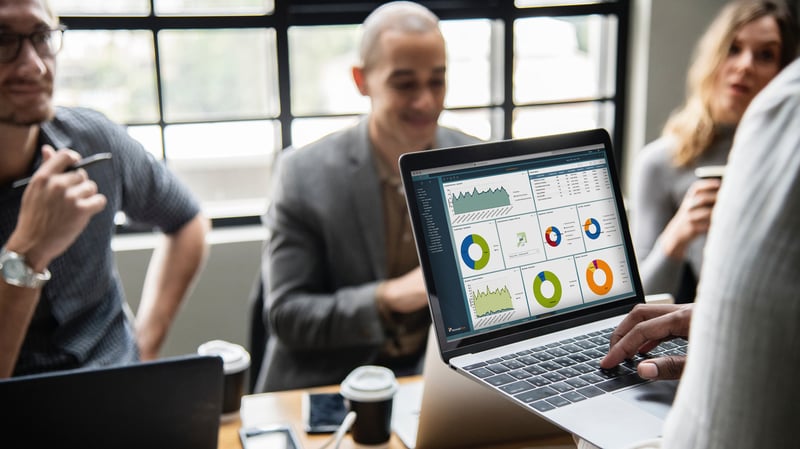 Ein Laptop auf dem ein Dashboard zu sehen ist wird bedient, dahinter sitzt ein Mann
