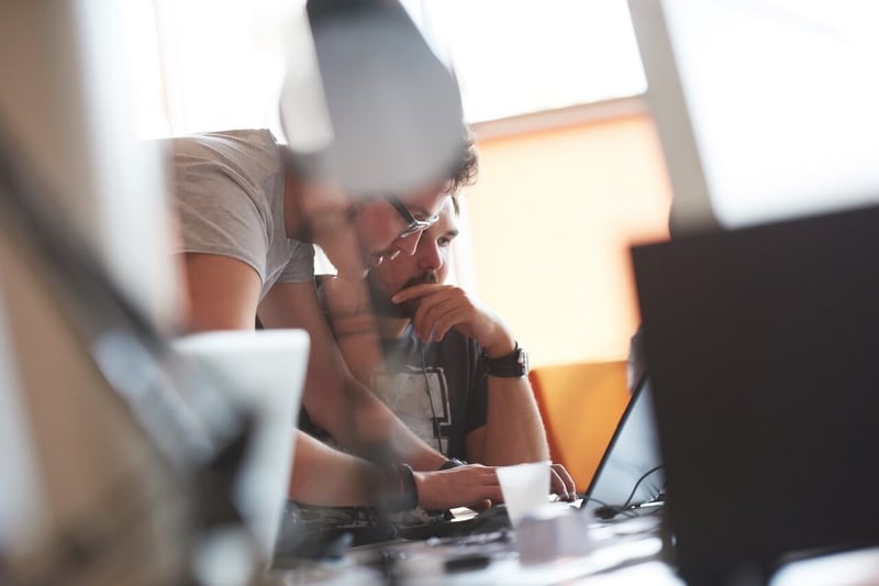 Zwei Männer, die an einem Laptop arbeiten, der auf dem Tisch steht