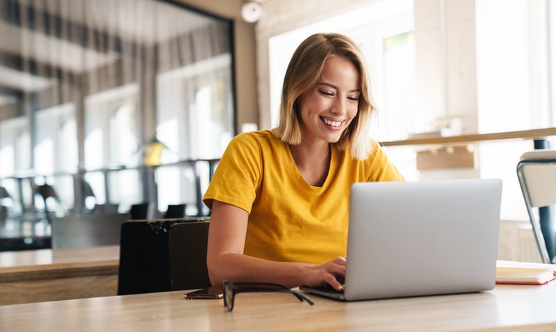 Eine lächelnde Frau sitzt vor einem Laptop