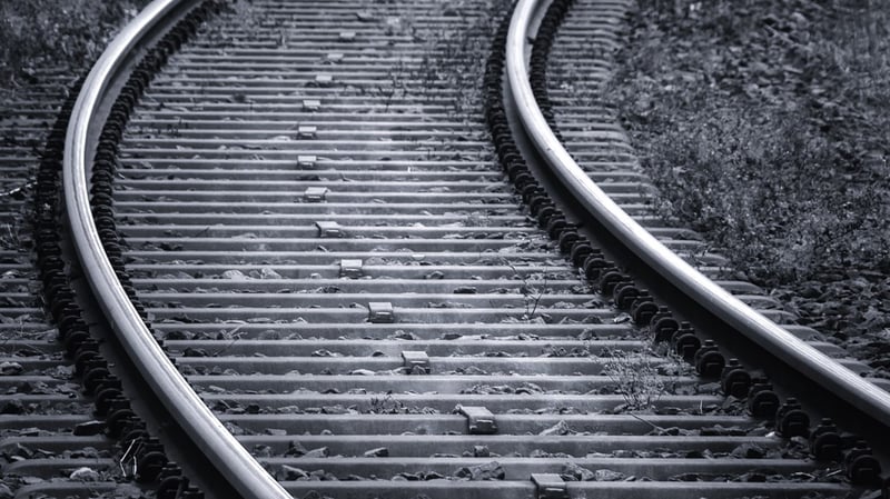 Schwarz-weiß Aufnahme von gebogenen Bahngleisen.