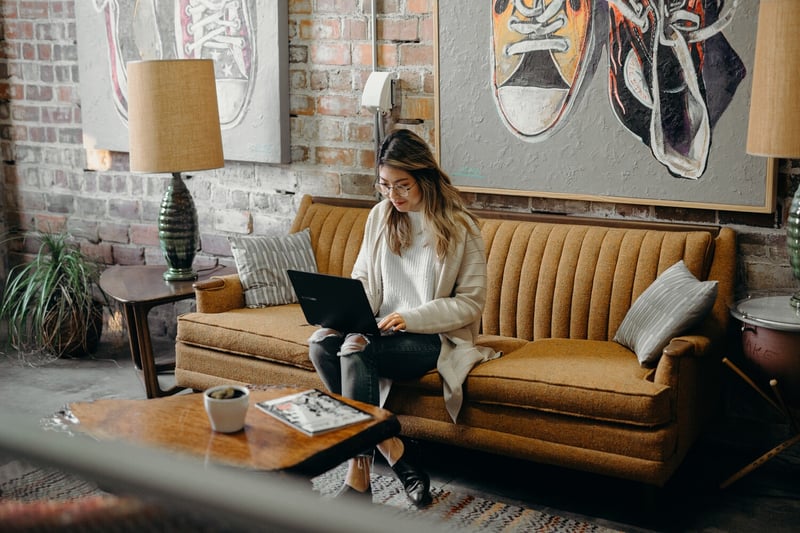 Eine Frau sitzt mit ihrem Laptop auf einer Couch