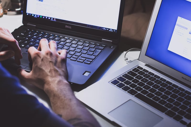 Mann arbeitet an zwei Laptops