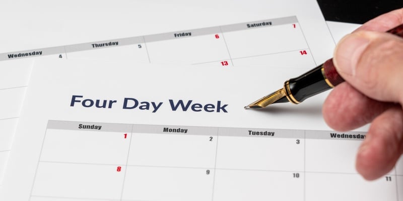 Kalender mit der Überschrift Vier Tage Woche und einer Hand, die einen Füller hält