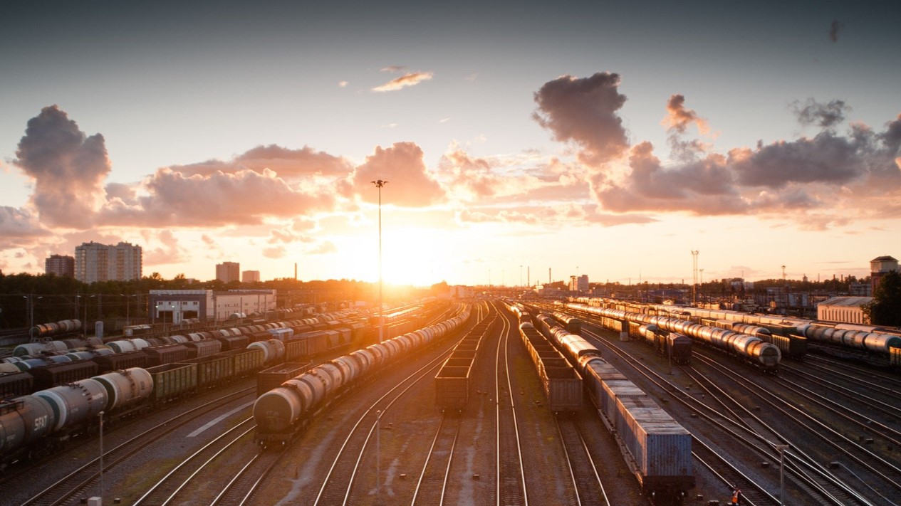 Bahnhofsgelände mit Güterzügen bei Sonnenuntergang